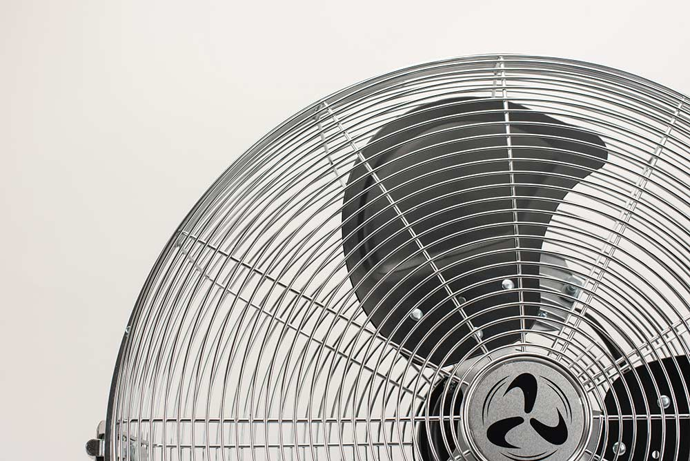 Nahaufnahme eines silbernen Ventilators mit schwarzem Klingenschutz.