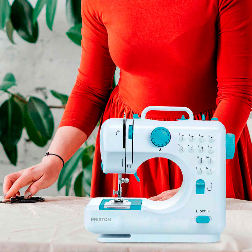 Biała maszyna do szycia stoi na stole, kobieta do niej sięga. Czerwona sukienka w tle.