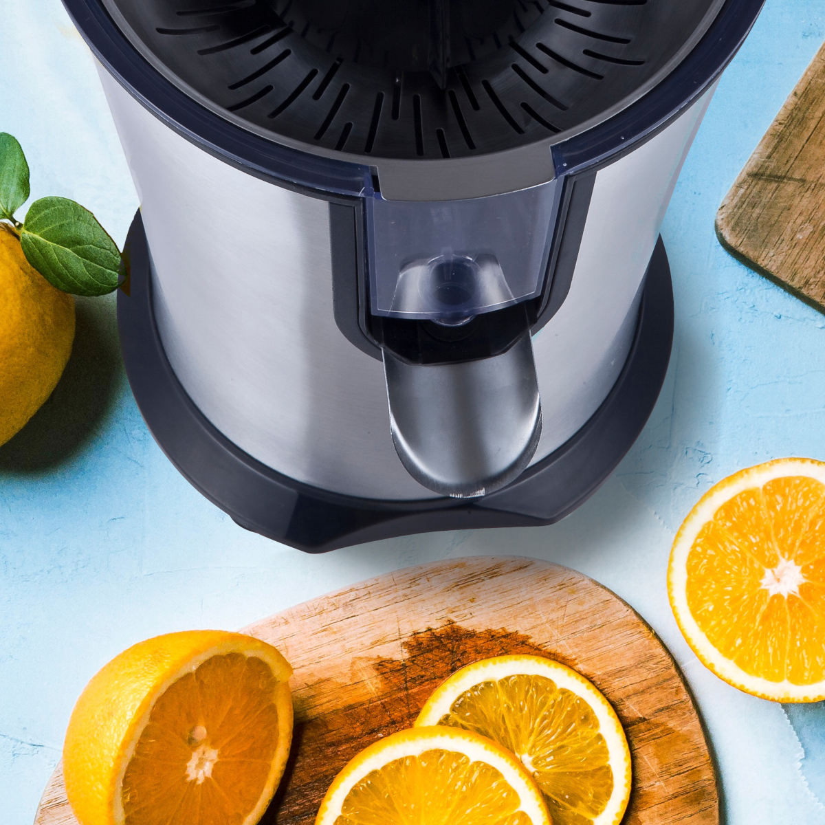 Wyrażalnik z pomarańczami i drewnianymi deskami do krojenia. Niebieskie tło.