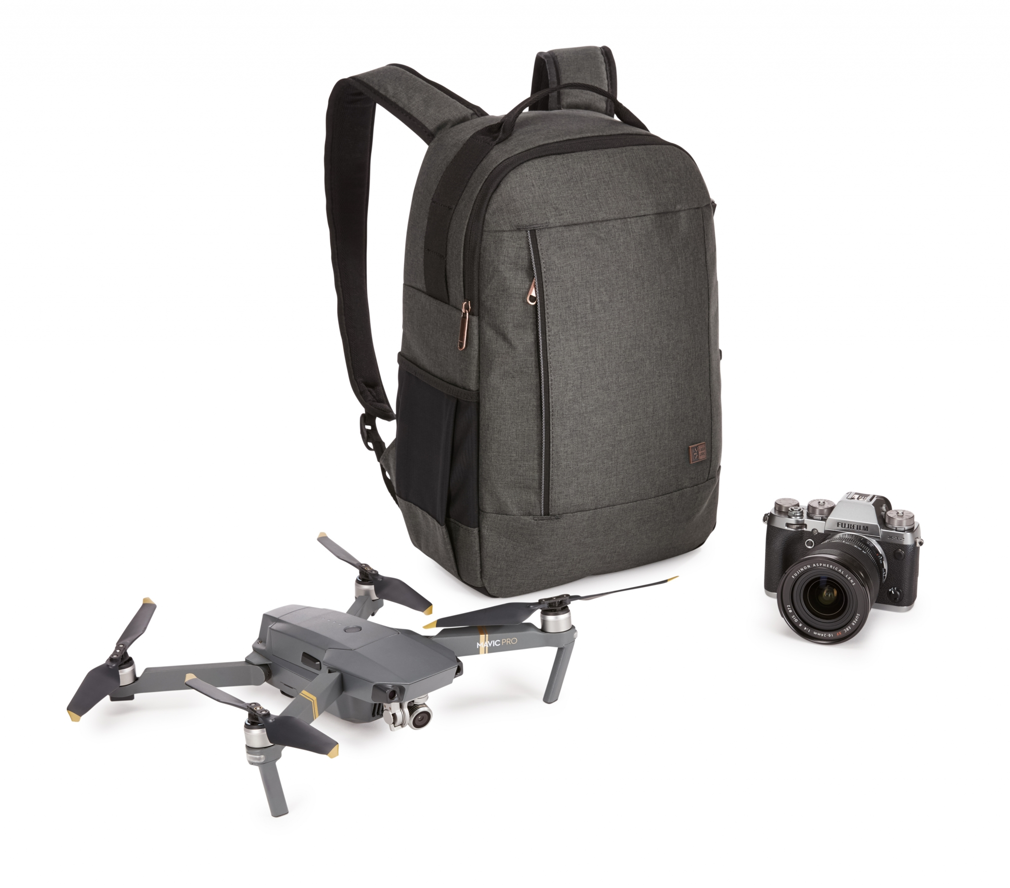 Uno zaino, un drone e una fotocamera sono disposti su una superficie bianca, pronti per un viaggio.