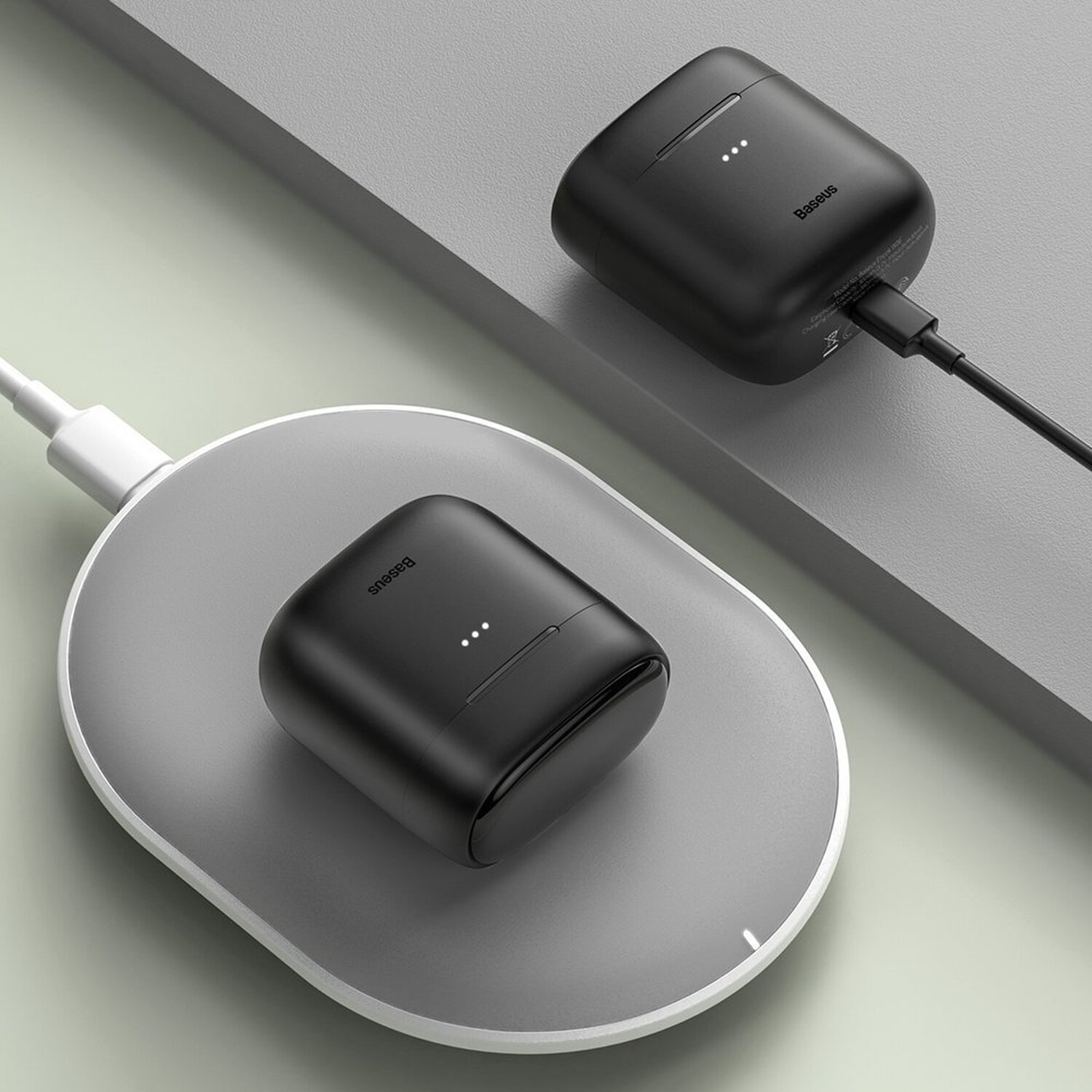Zwei schwarze kabellose Ohrhörer-Ladecases befinden sich auf einem grauen Ladepad mit angeschlossenem weißen Kabel.