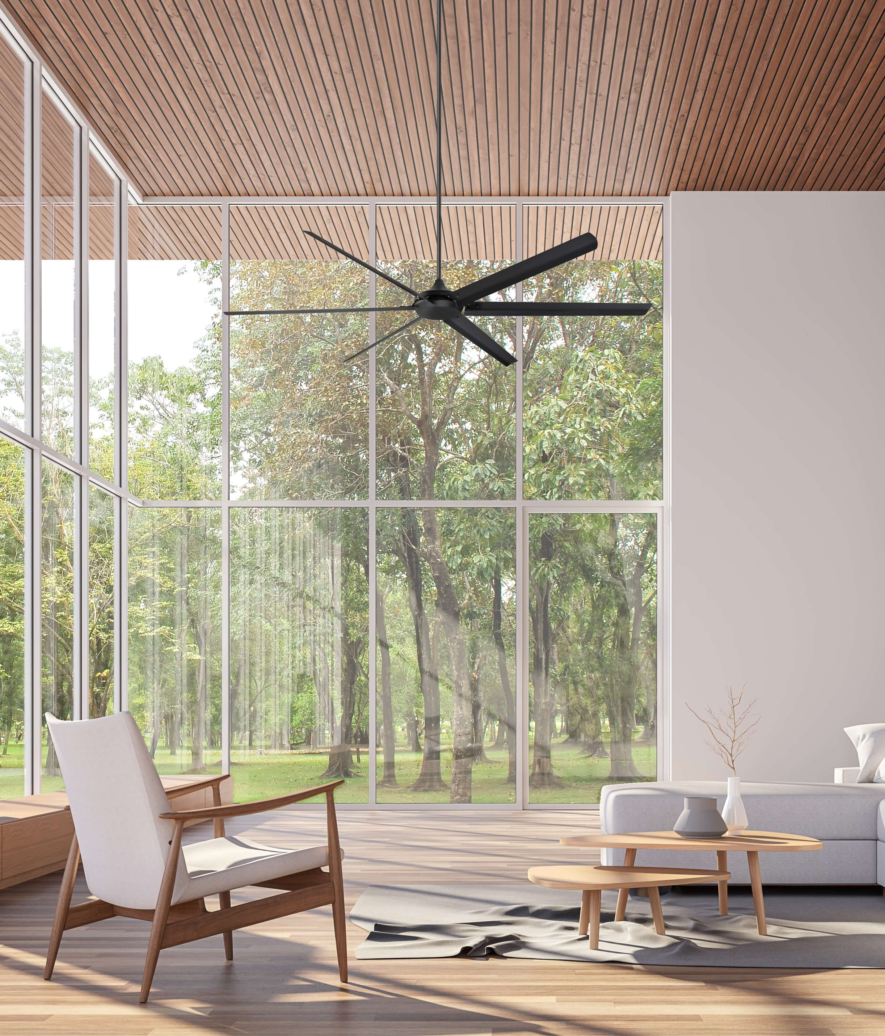 Modernes Wohnzimmer mit großen Fenstern. Ein schwarzer Deckenventilator hängt über dem Sitzbereich.