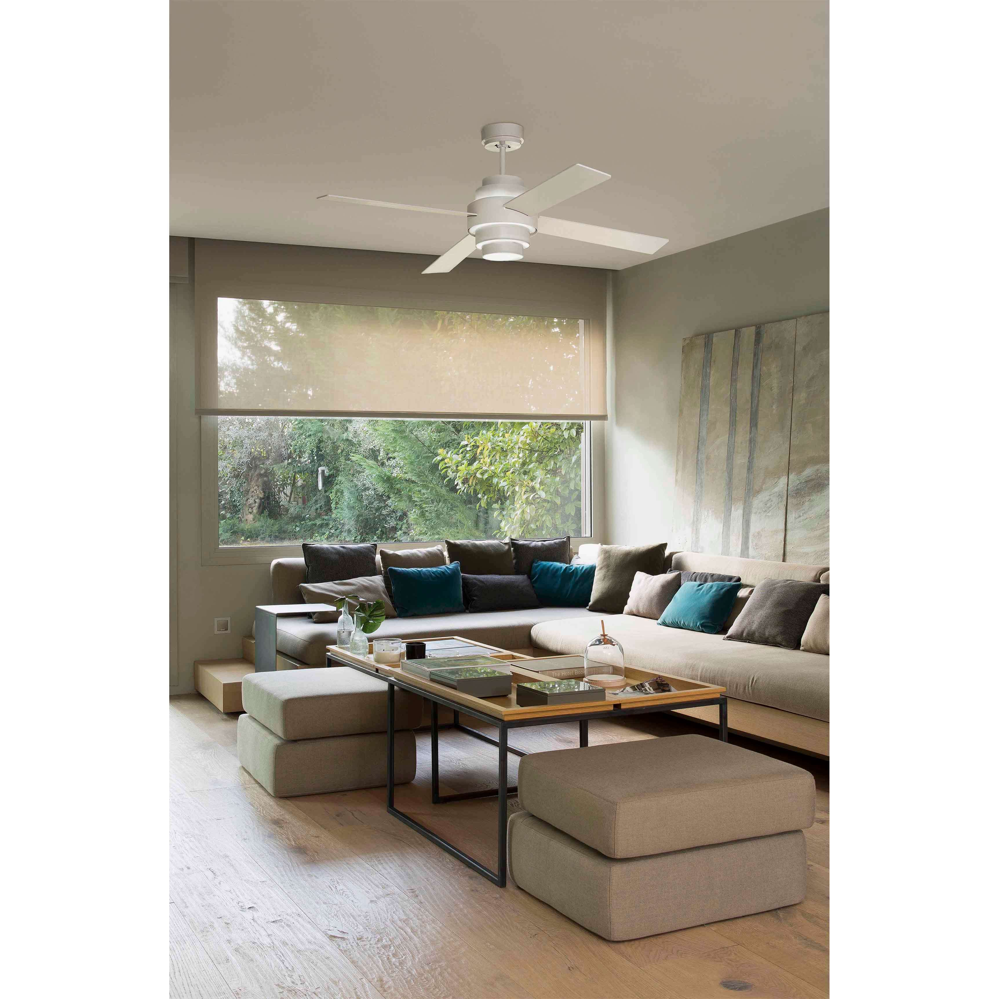 Wohnzimmer mit beigem Sofa, Deckenventilator, Couchtisch und großem Fenster mit Blick auf grüne Bäume.