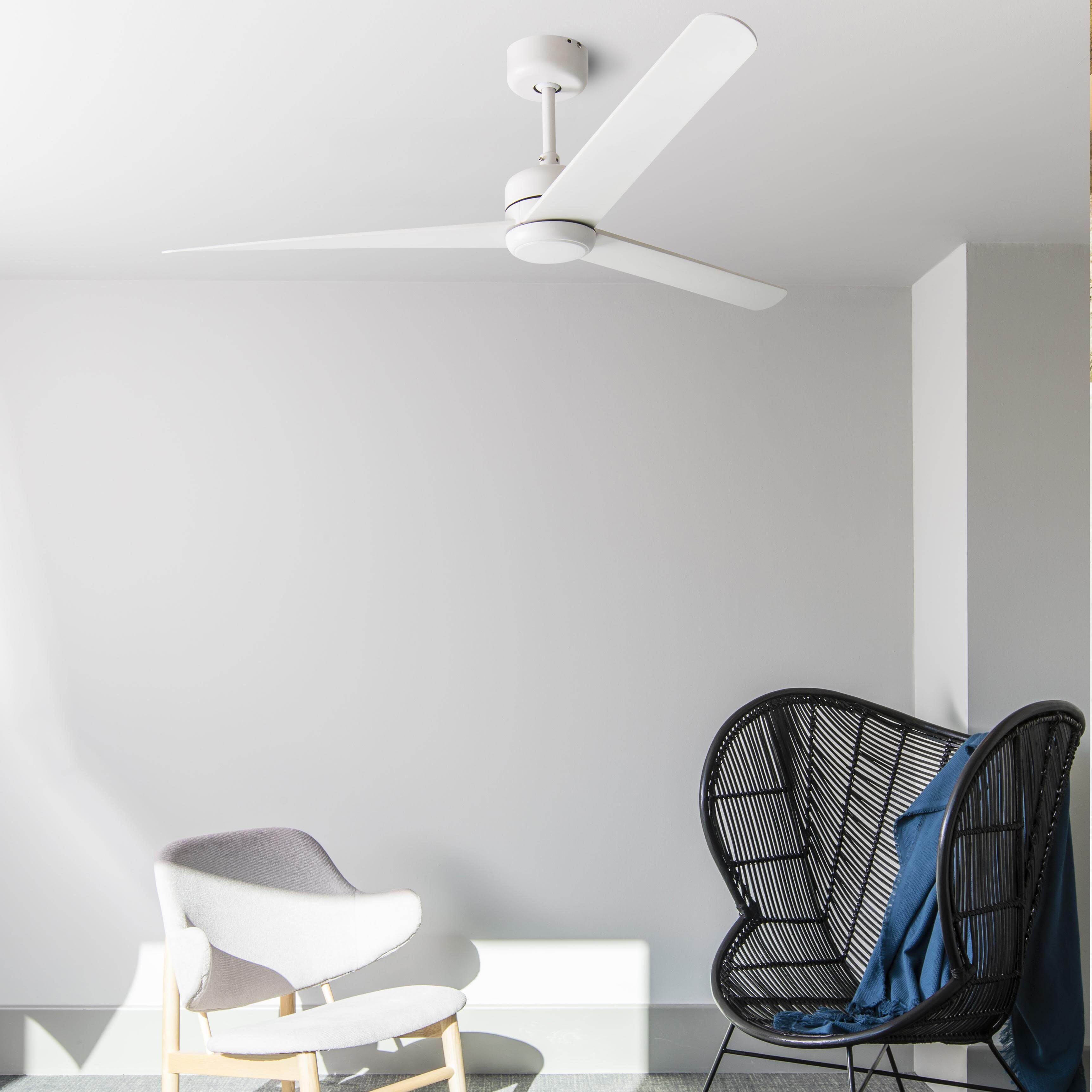 Weißer Deckenventilator mit drei Flügeln, der über zwei Stühlen in einem Raum mit weißen Wänden hängt.