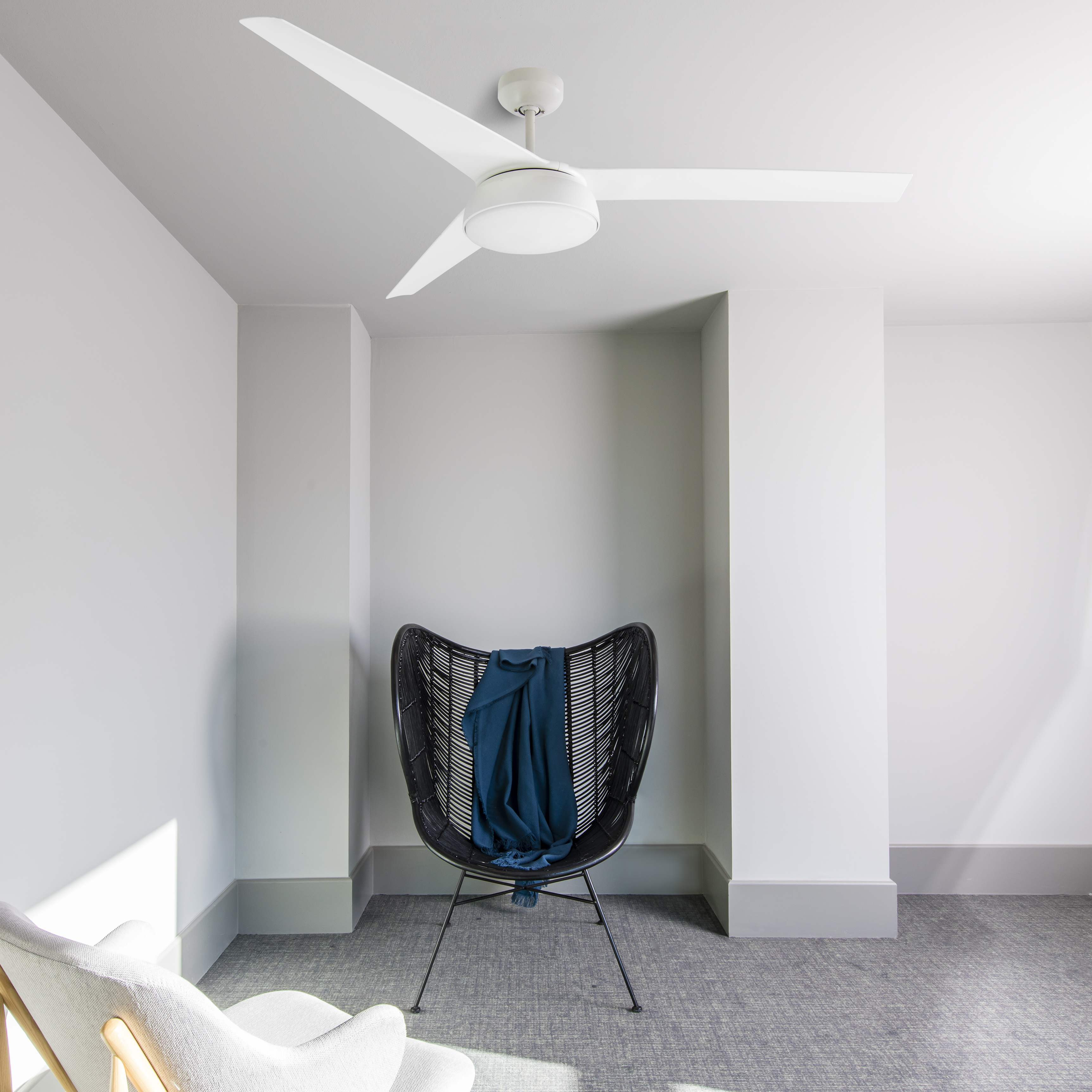 Raum mit Deckenventilator, schwarzem Stuhl mit blauer Decke und Teppichboden.