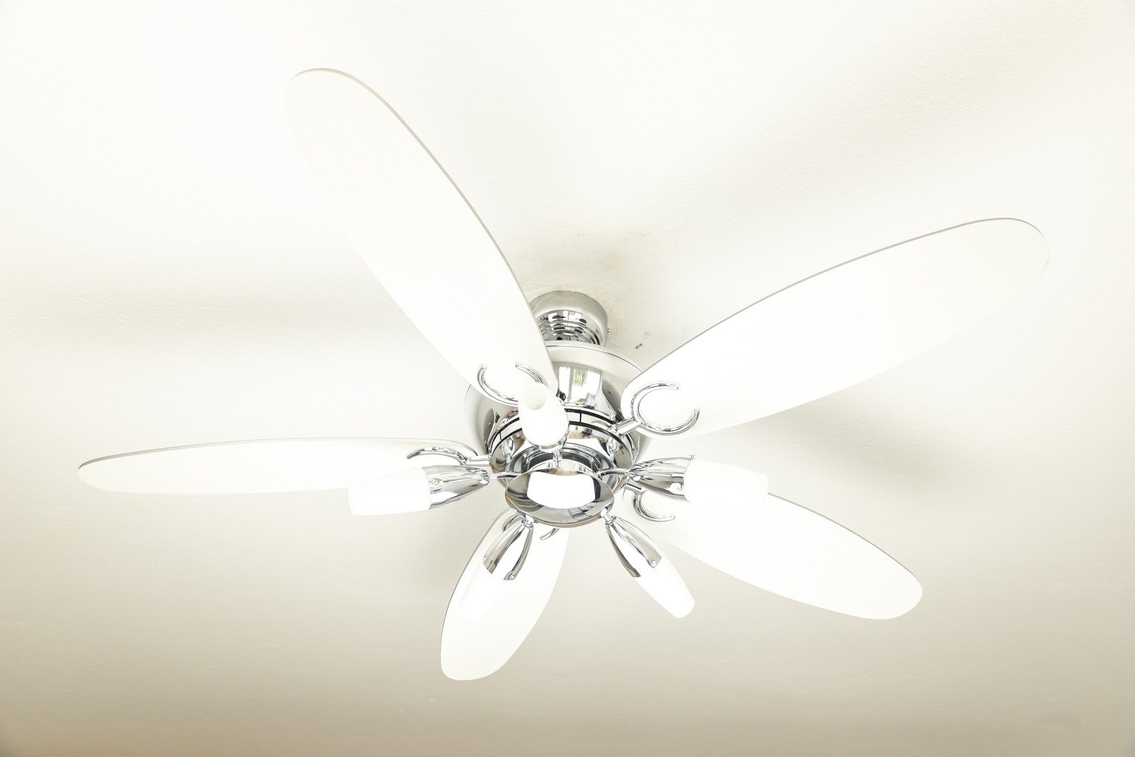 Weißer Deckenventilator mit fünf Flügeln und Chromakzenten. Von unten betrachtet.