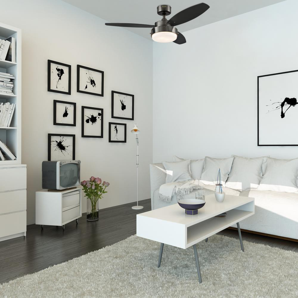 Stanza bianca con arte, un divano bianco e un ventilatore da soffitto nero. Include un tappeto, un tavolino e una TV.