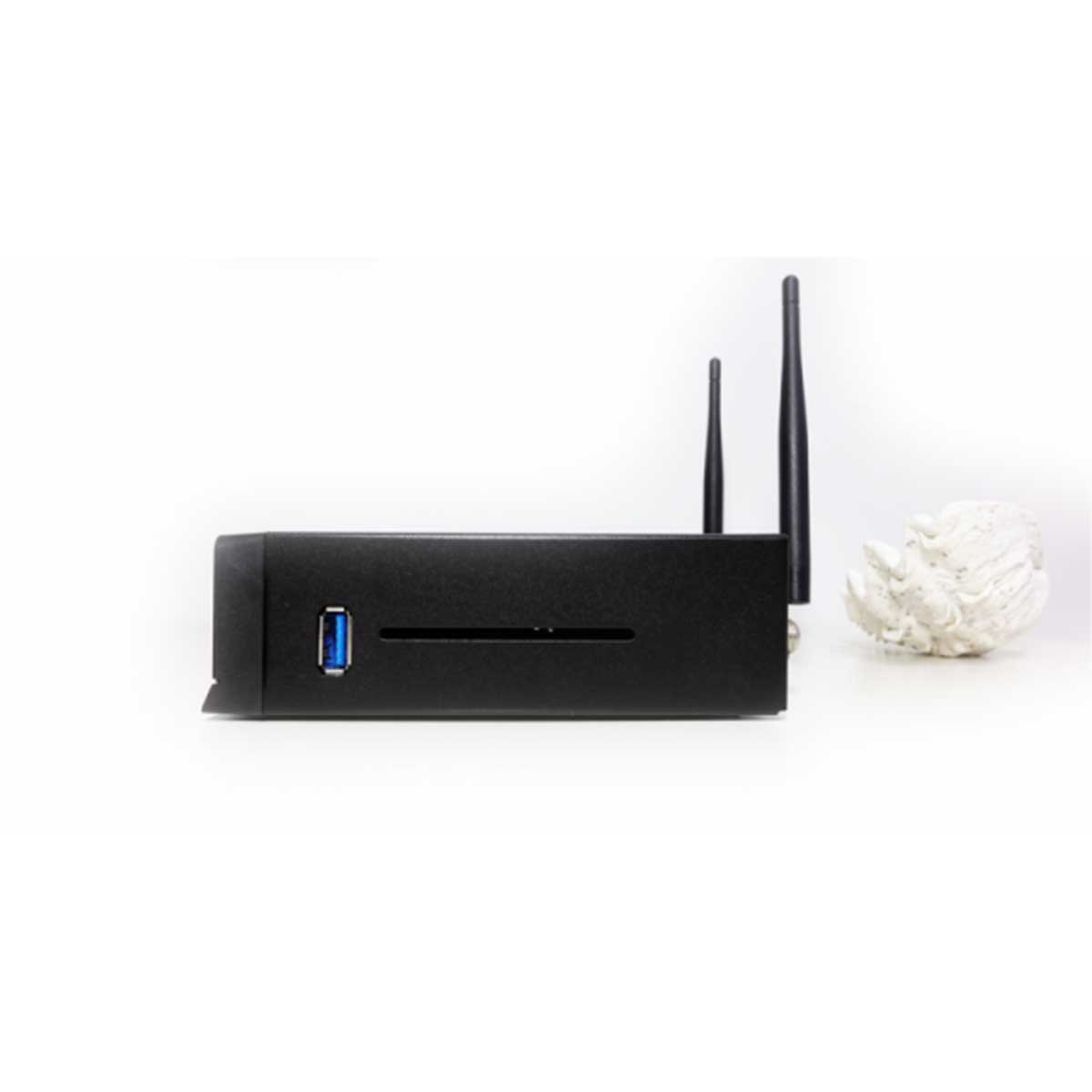 Ein schwarzes Gerät mit zwei Antennen und einem USB-Anschluss, neben einem weißen Dekorationsobjekt.