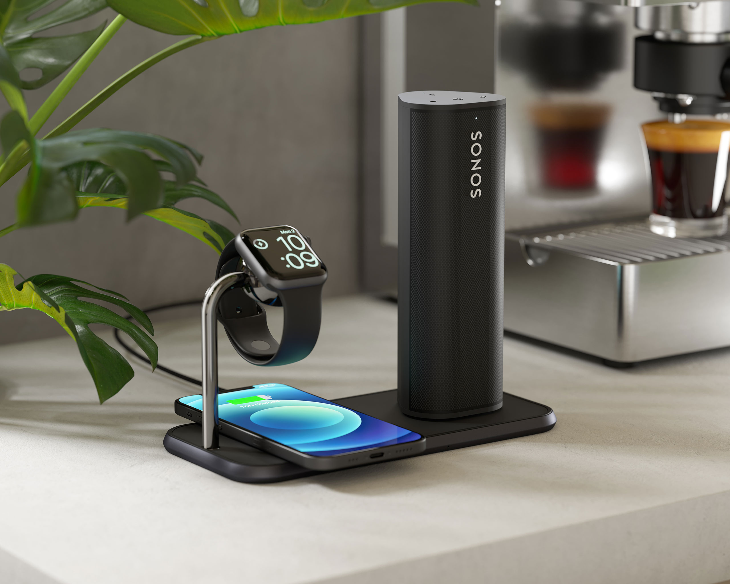 Ladestation mit Handy, Smartwatch und Lautsprecher. Im Hintergrund eine Kaffeemaschine.