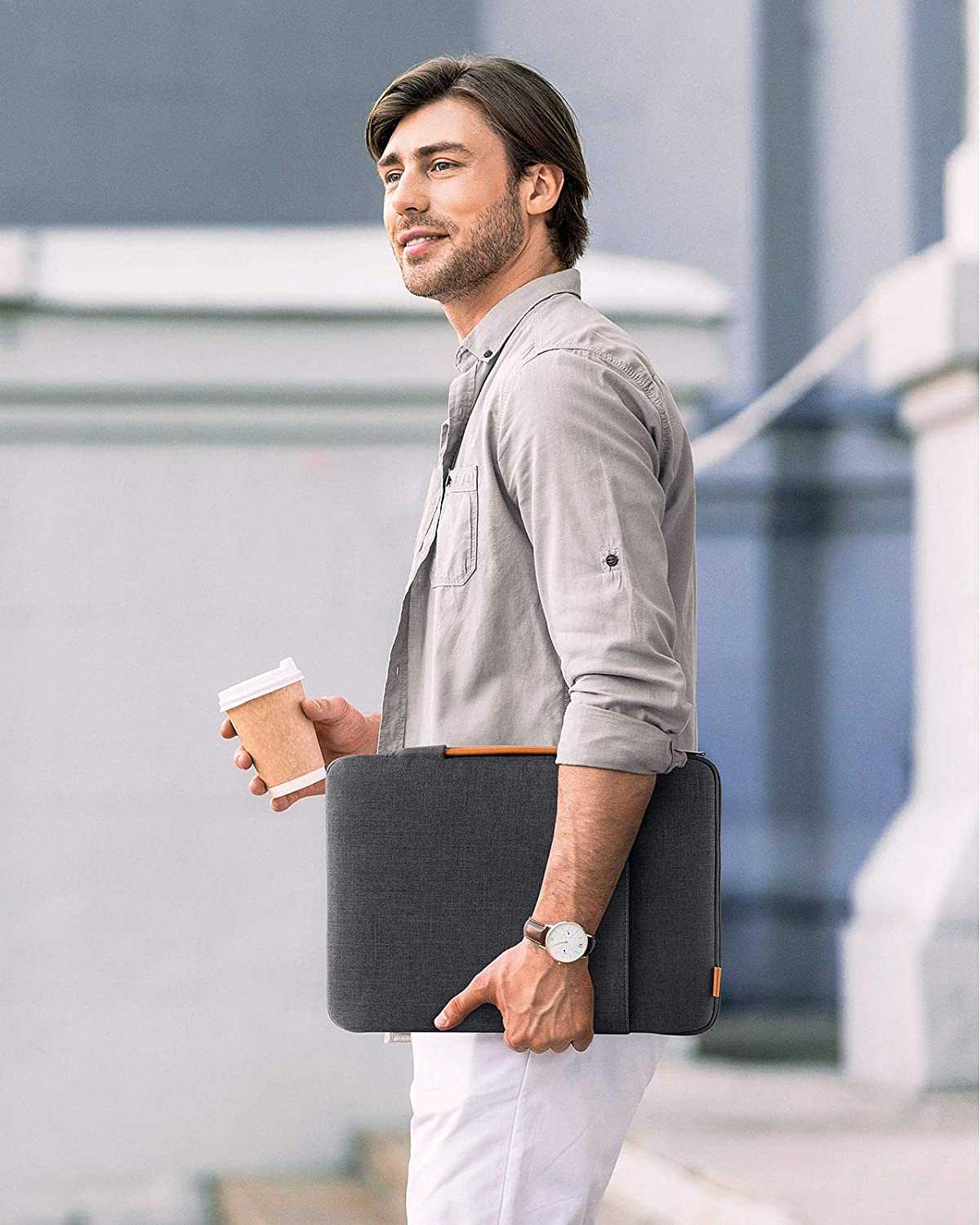 Mann hält eine Laptoptasche und eine Kaffeetasse. Er trägt eine Uhr.