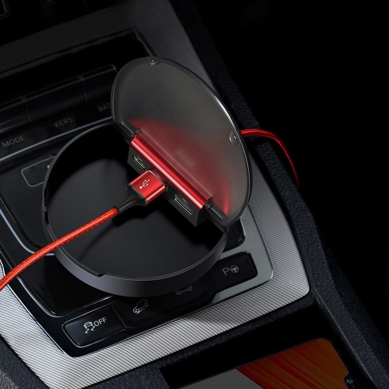 Ein schwarzer USB-Hub für das Auto mit einem roten USB-Kabel. Der Hub befindet sich in der Konsole.