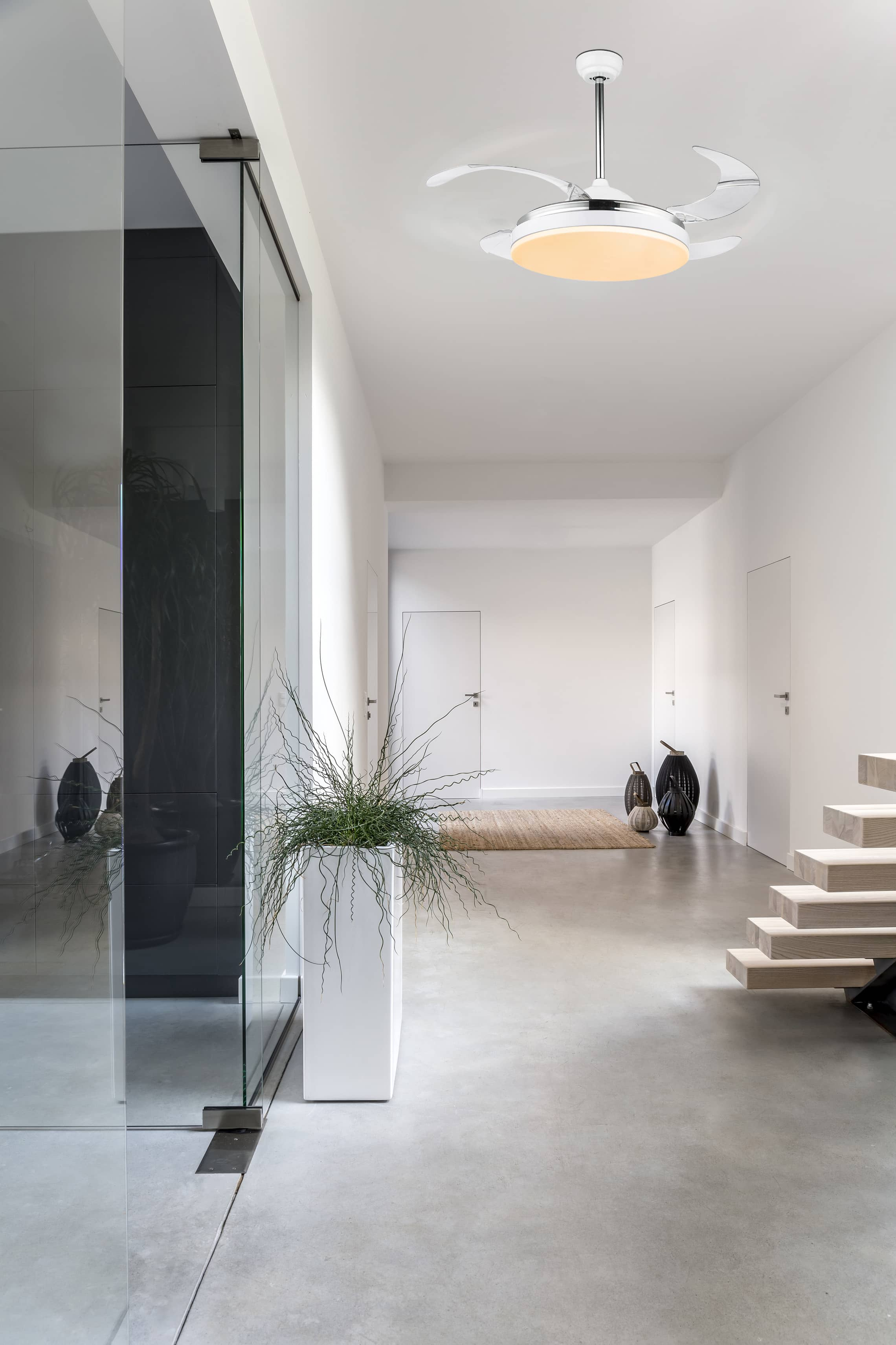 Moderner Flur mit Deckenventilator, weißen Wänden, Glastür und Holztreppe.