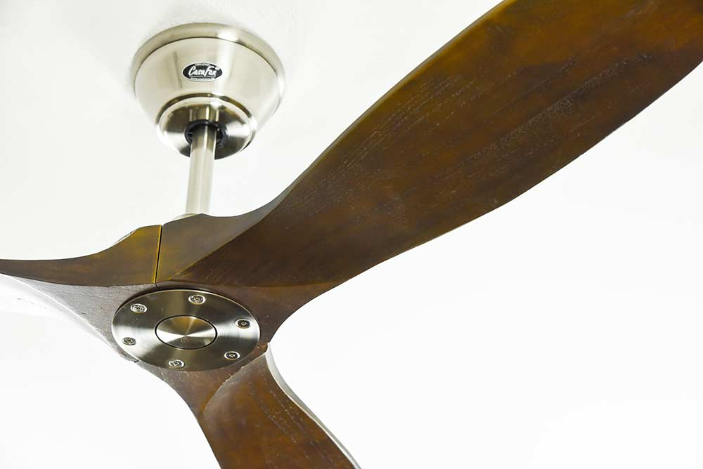 Primo piano di un ventilatore da soffitto con pale in legno e centro metallico.
