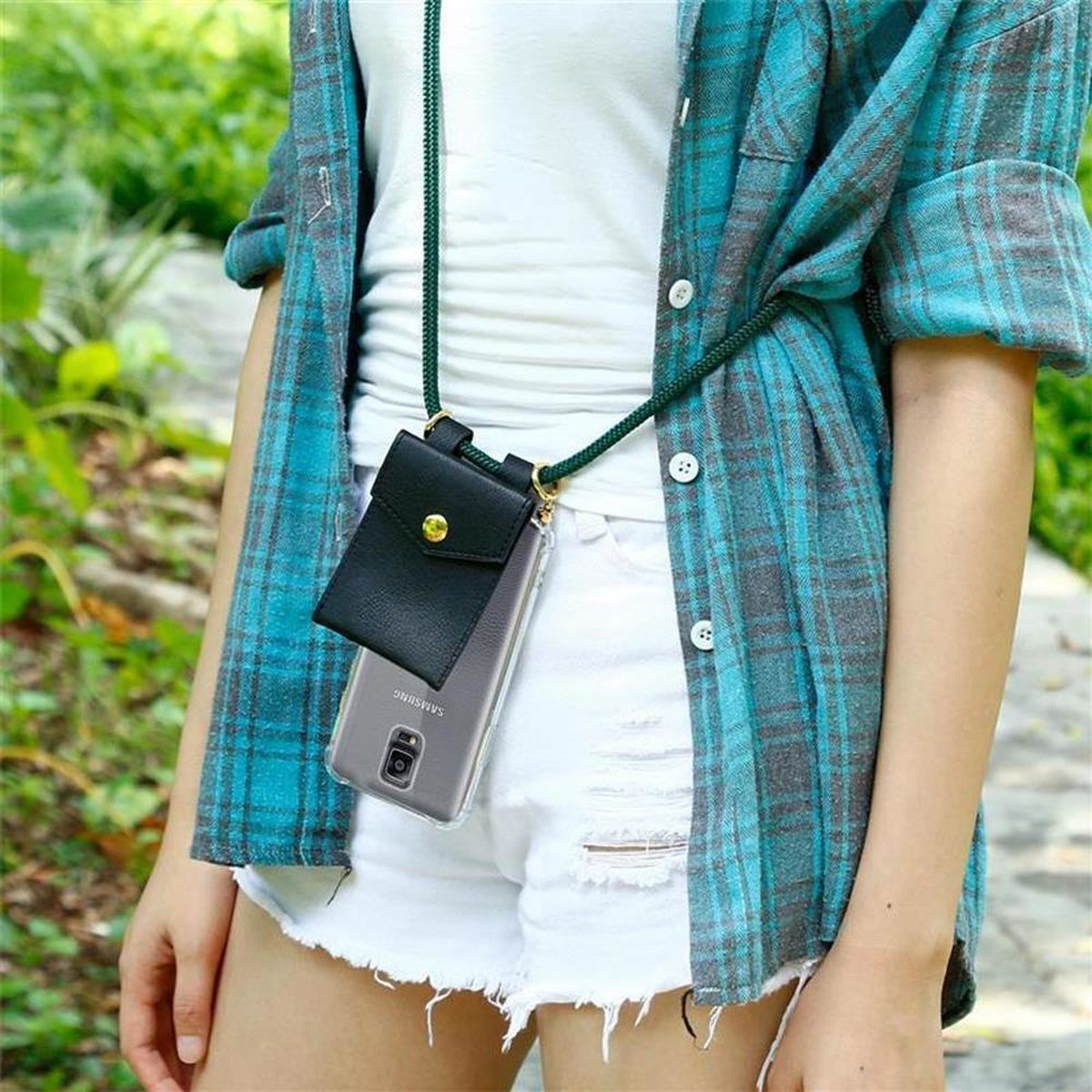 Donna con camicia a quadri blu e pantaloncini bianchi. Custodia nera con cordino verde al collo.