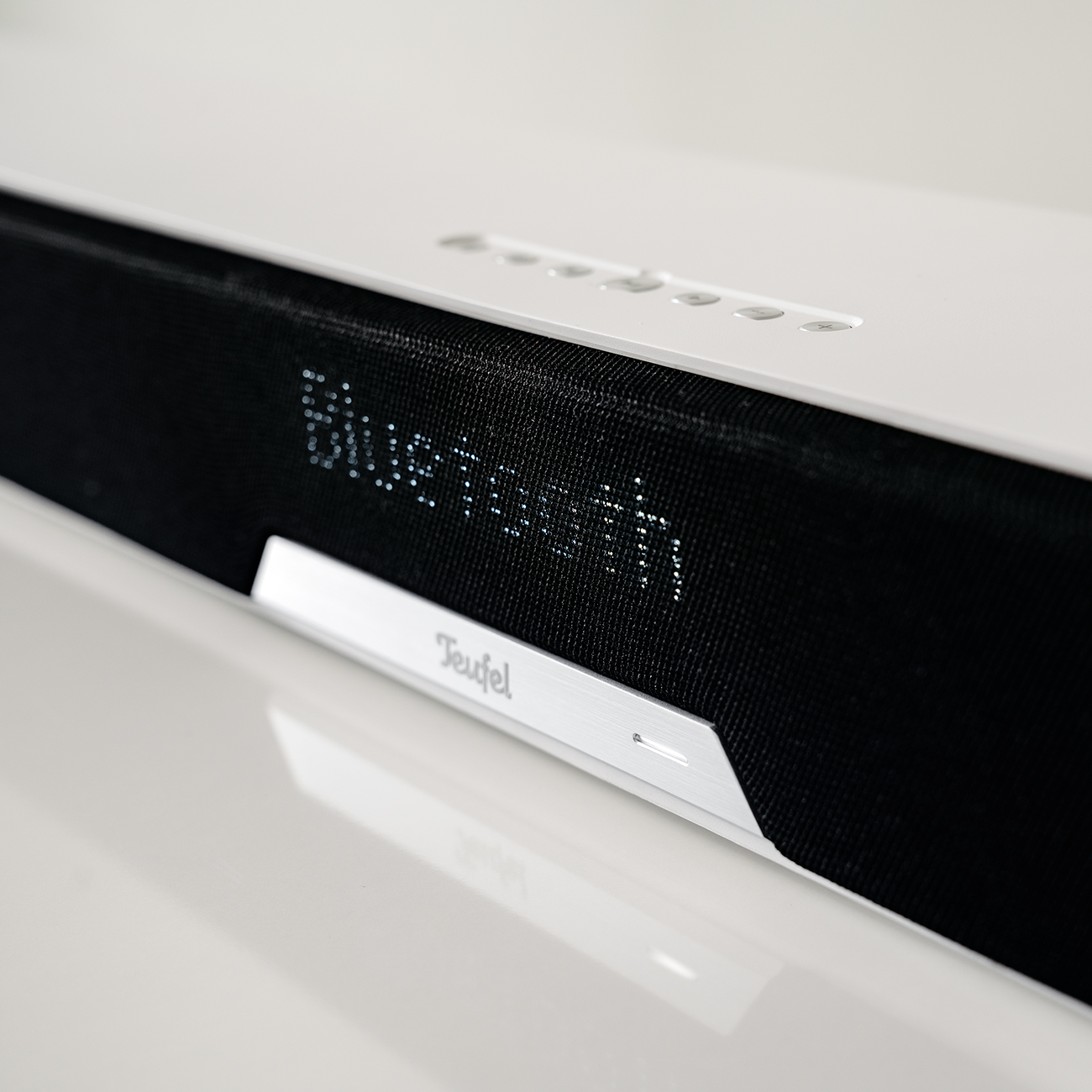Nahaufnahme einer weißen Soundbar mit dem Wort 'Bluetooth'.