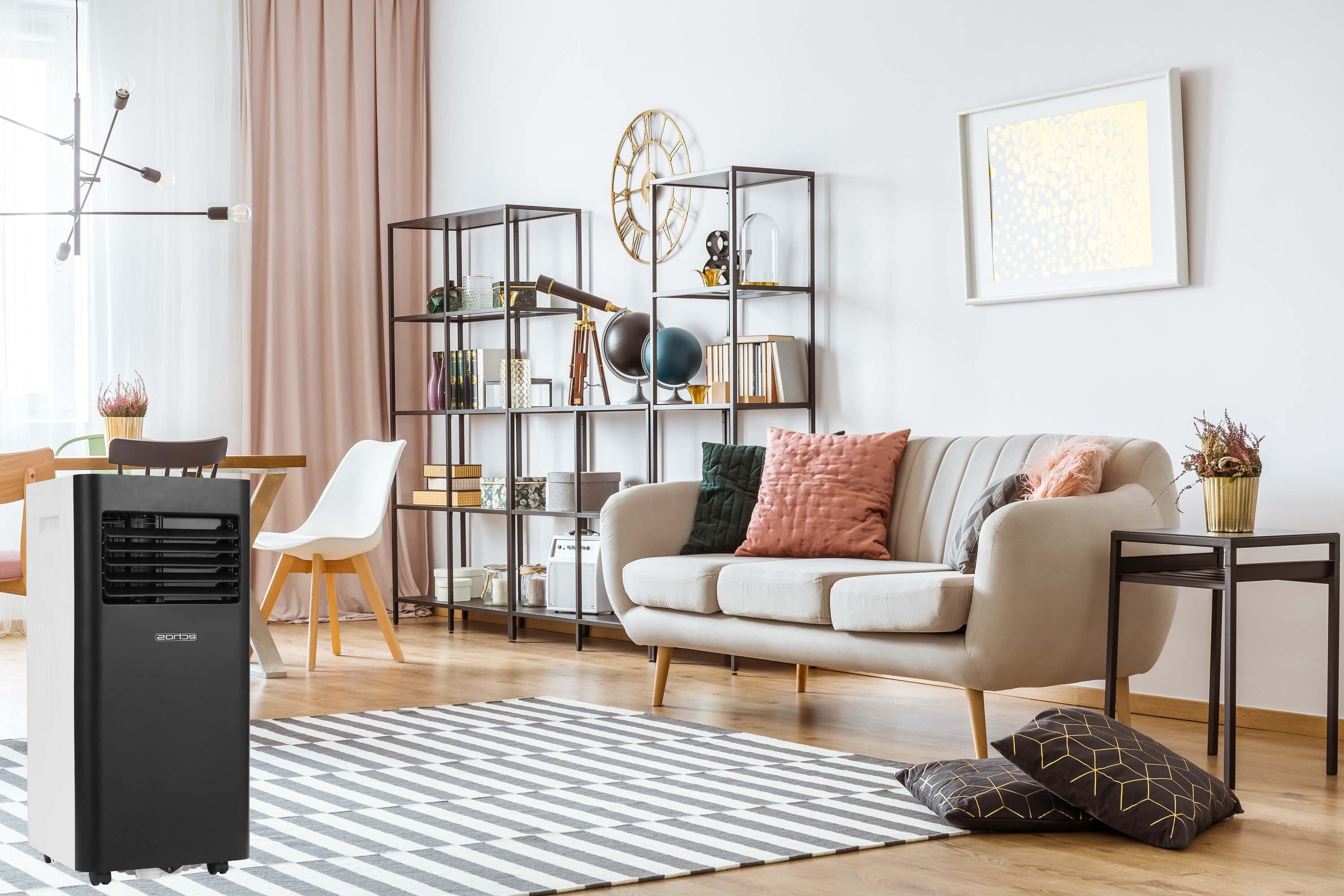 Ein schwarz-weißer Luftkühler steht auf der linken Seite eines Raumes. Rechts befindet sich ein Sofa.