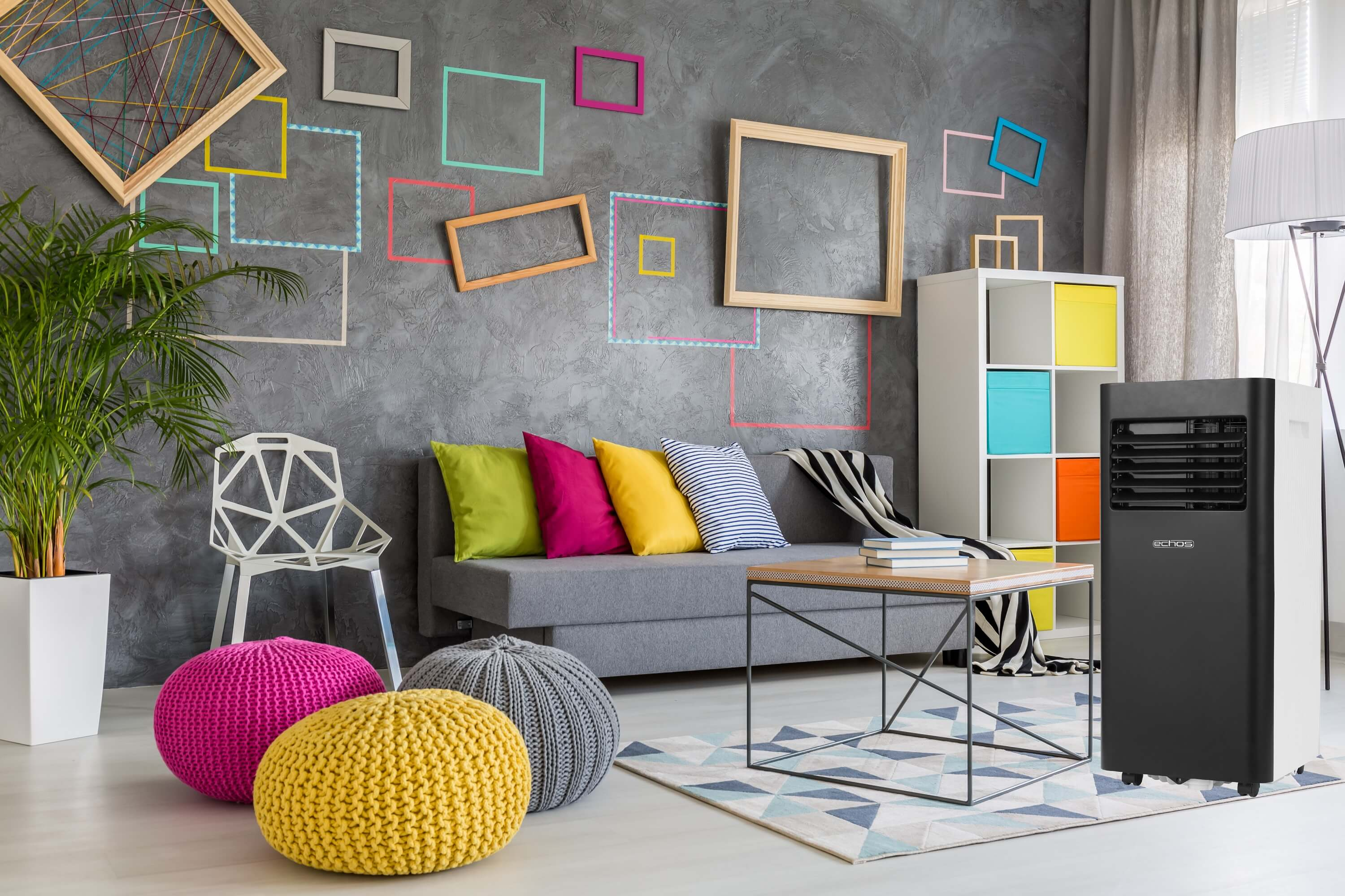 Wohnzimmer mit grauem Sofa, bunten Kissen und einem Luftkühler.