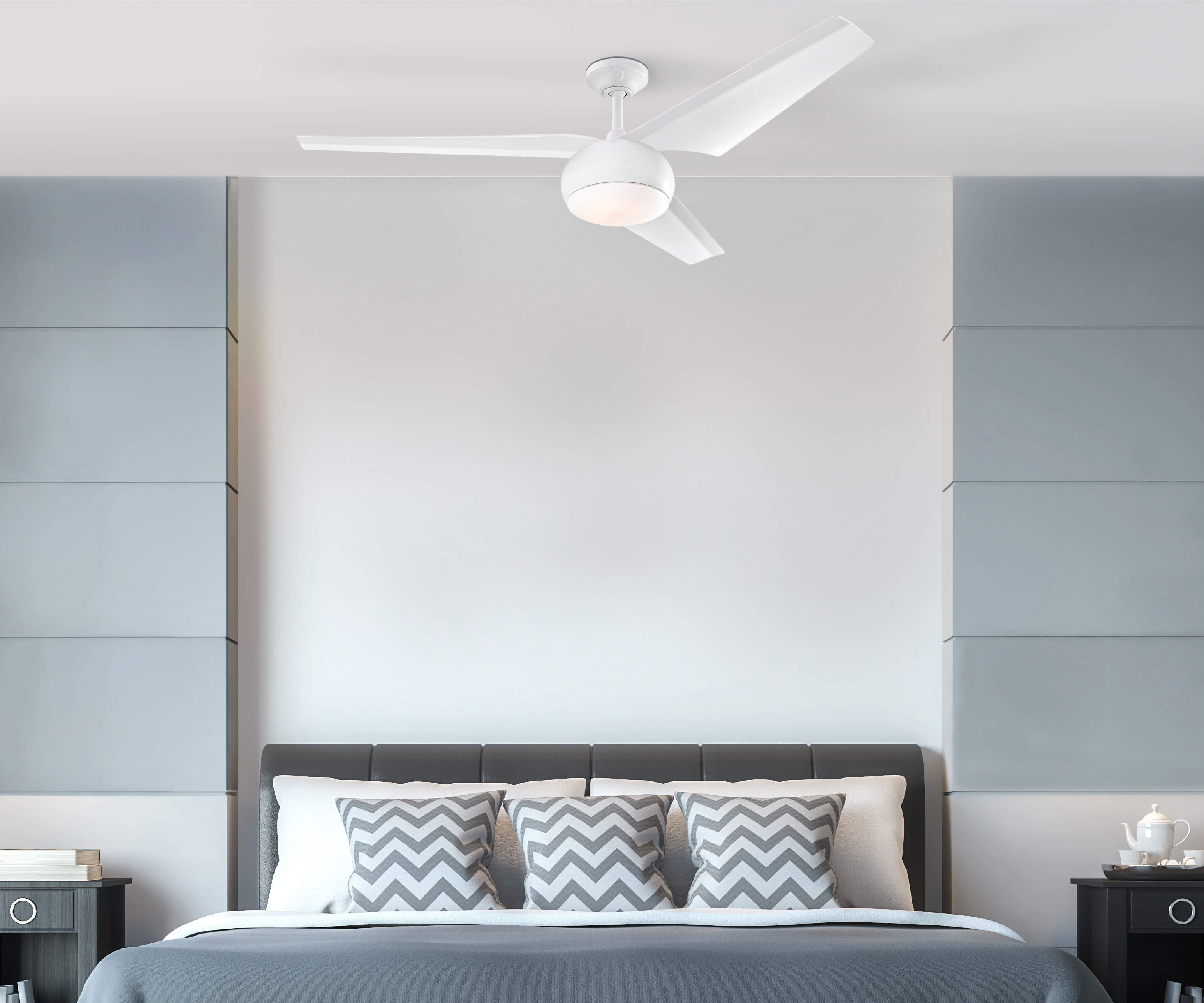 Ein Schlafzimmer mit weißem Deckenventilator, Bett mit Kissen und neutralem Farbschema.