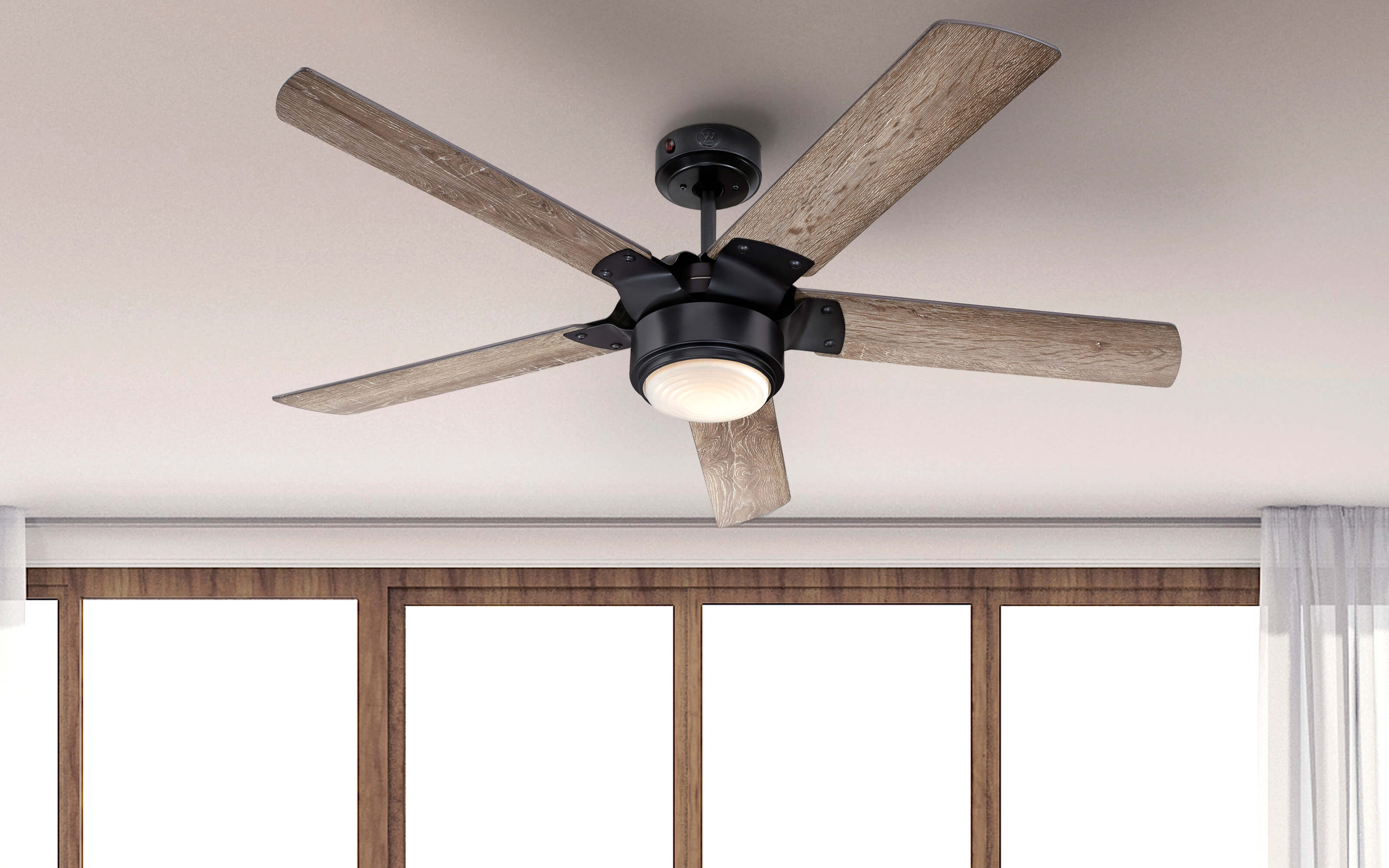 Deckenventilator mit fünf braunen Flügeln. Montiert an einer weißen Decke mit einem braunen Rand.