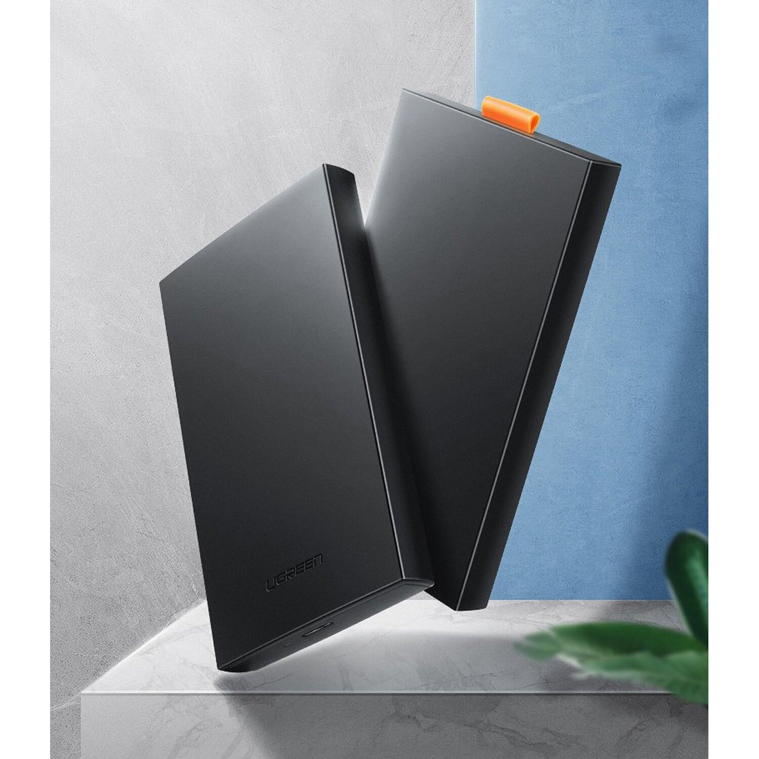 Dwa czarne zewnętrzne dyski twarde stojące na powierzchni, jeden z pomarańczową zakładką.