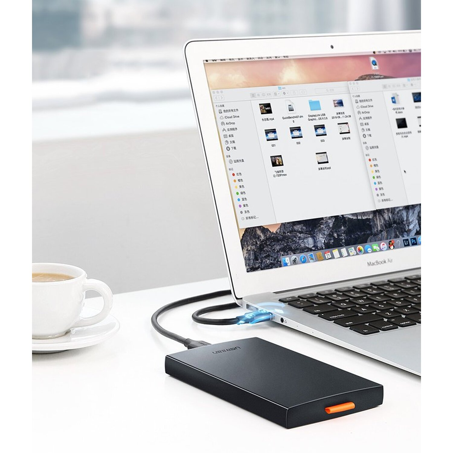 Laptop podłączony do czarnego zewnętrznego dysku twardego kablem USB, z białą filiżanką.