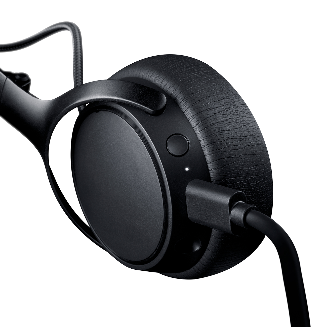 Un auricular negro con un cable enchufado. El auricular tiene un botón y una luz.