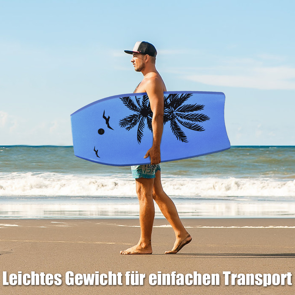 Mann trägt ein blaues Bodyboard am Sandstrand in der Nähe des Meeres mit Palmenmuster.