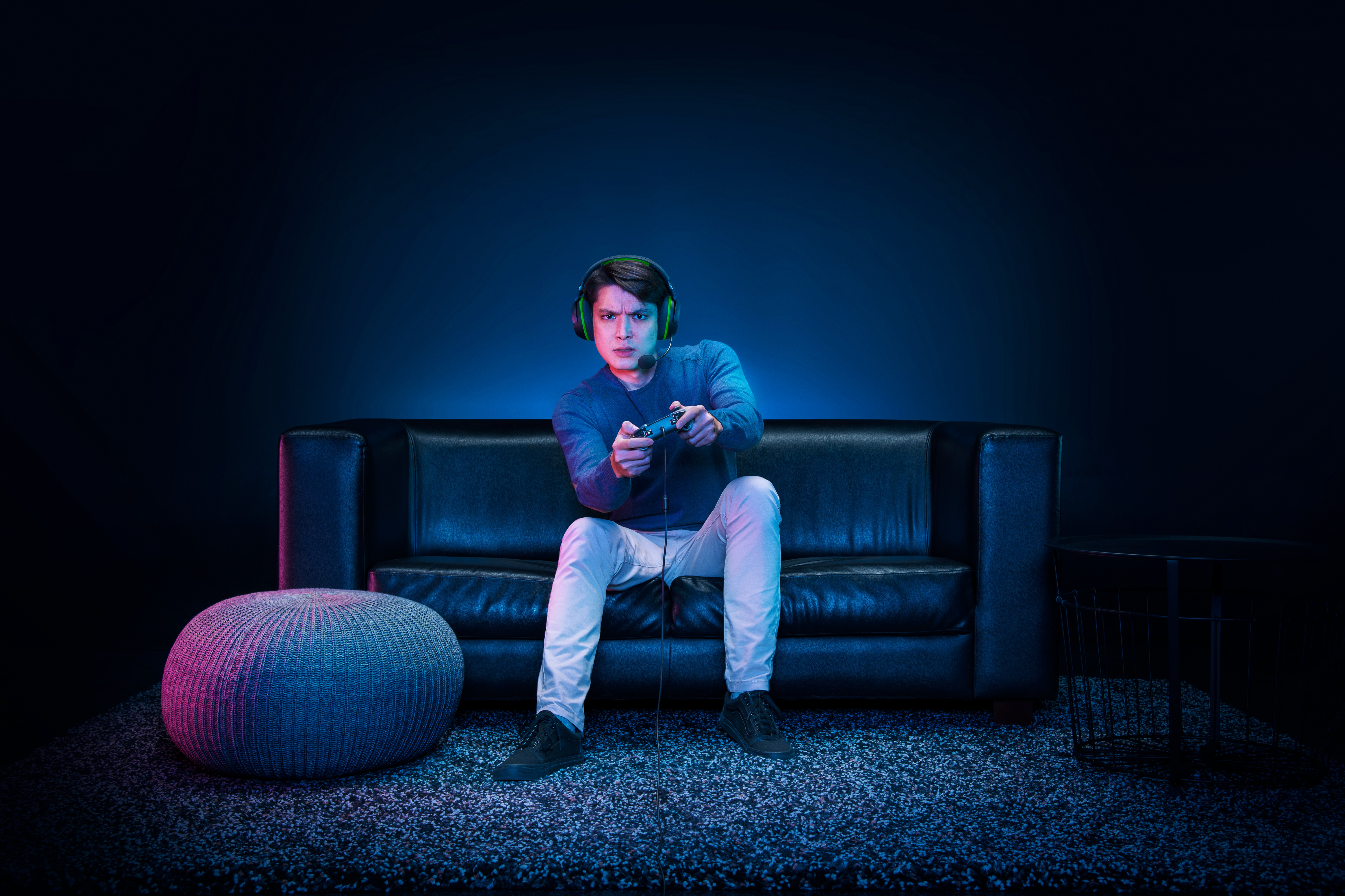 Spieler auf schwarzem Sofa, spielt. Er trägt ein Headset und hält einen Controller.