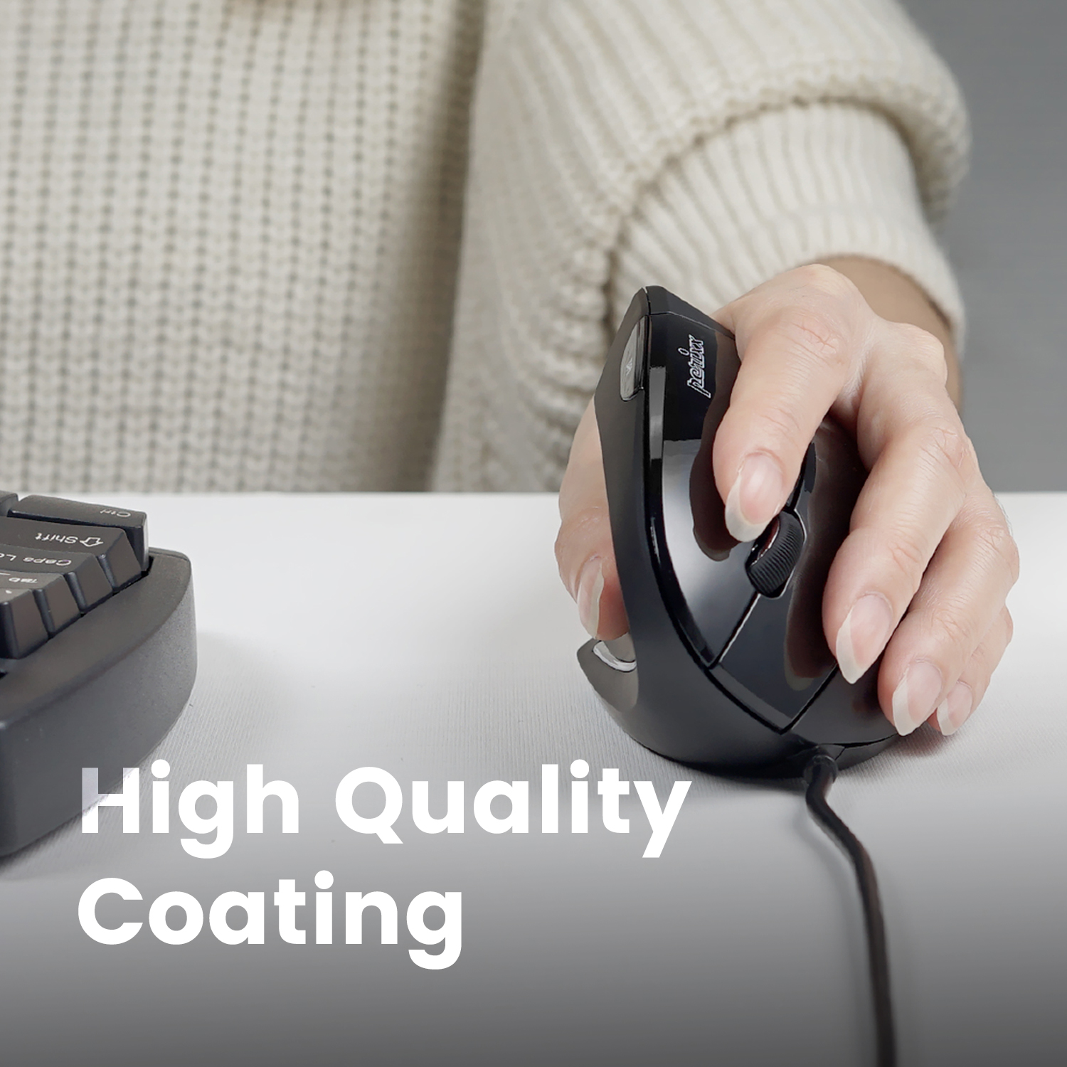 Czarna ergonomiczna mysz na białym stole, dłoń na niej. Tekst: Powłoka wysokiej jakości.