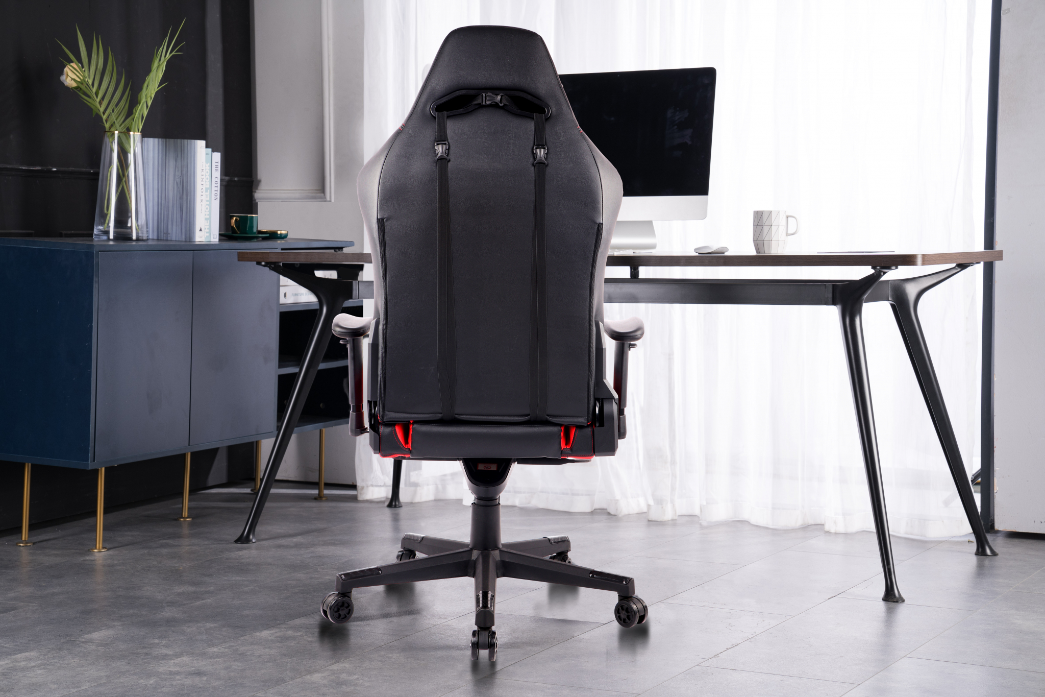 Gaming-Stuhl von hinten, mit schwarzen und roten Akzenten. Innenraum-Hintergrund.