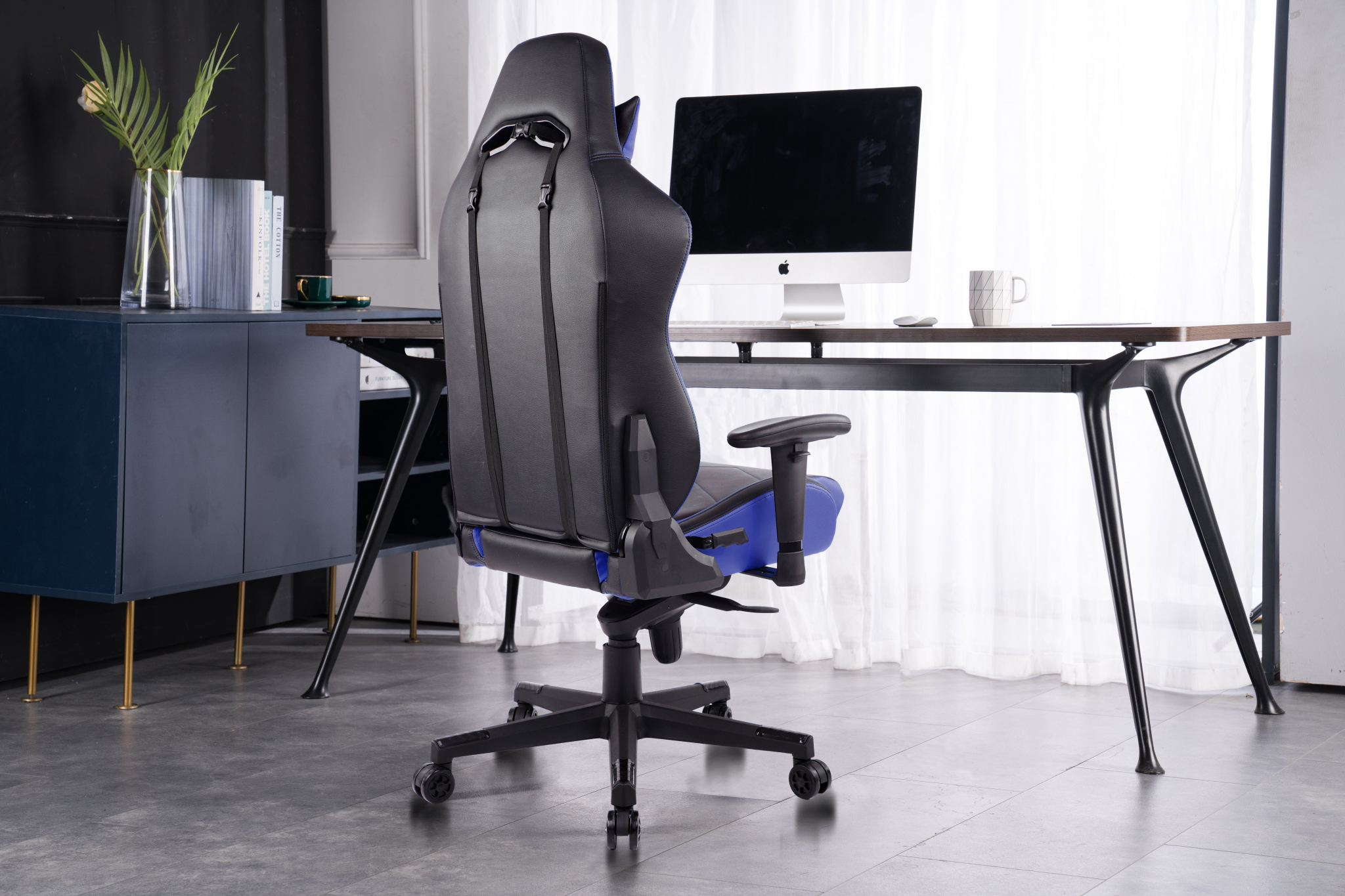 Gaming-Stuhl in einem Raum mit Schreibtisch, Monitor und Schrank.