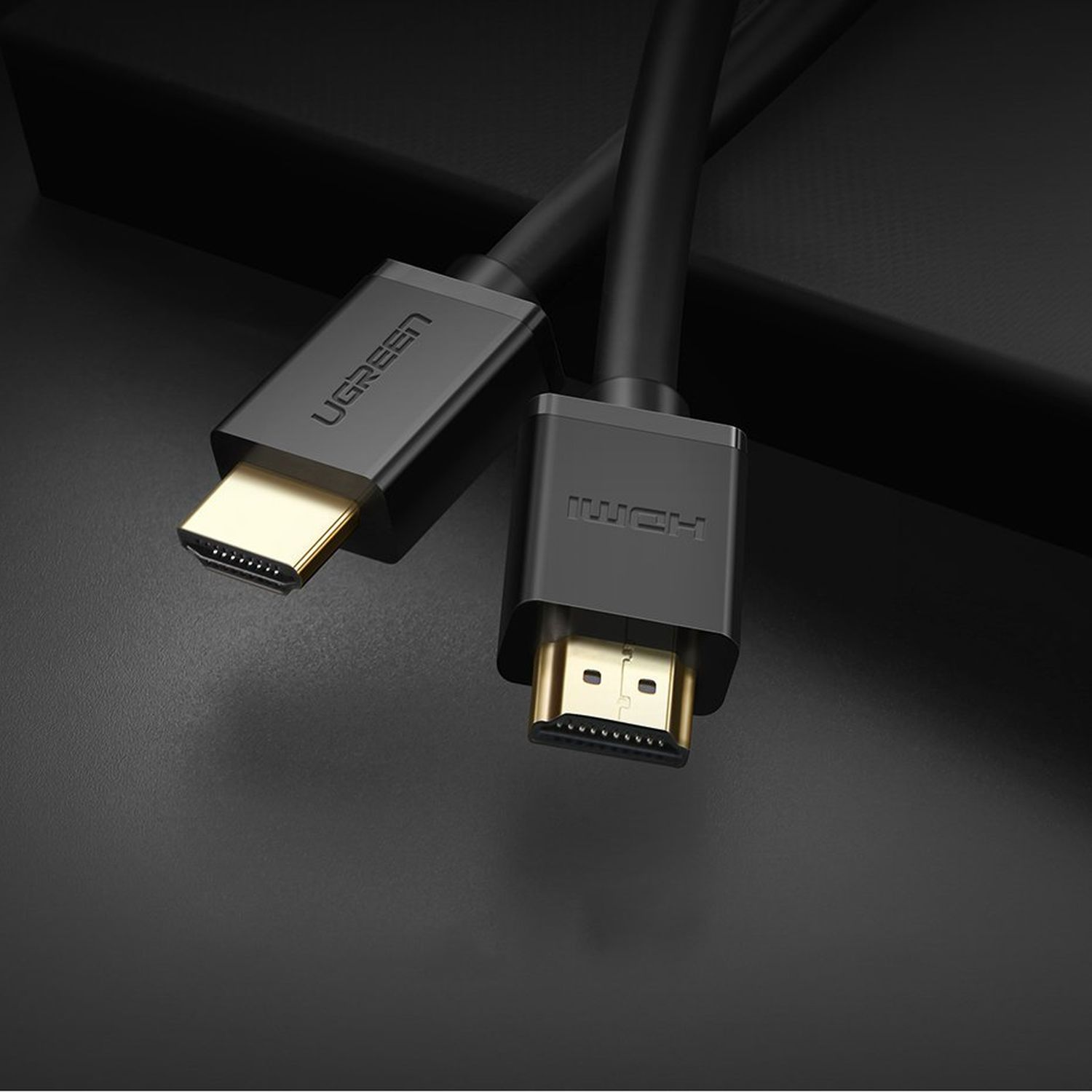 Schwarze HDMI-Kabel mit goldenen Steckern, auf dunkler, grauer Oberfläche mit geringer Tiefenschärfe.