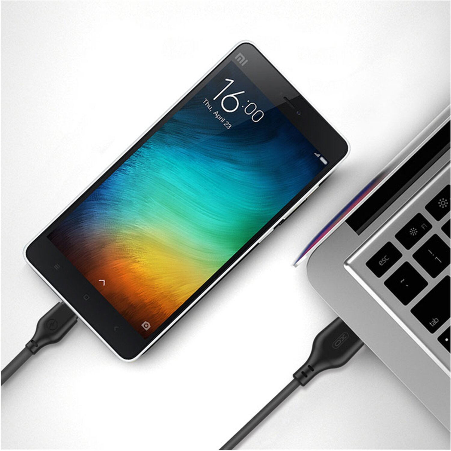 Ein Smartphone, das über ein USB-Kabel mit einem Laptop verbunden ist. Das Telefon zeigt 16:00 an.