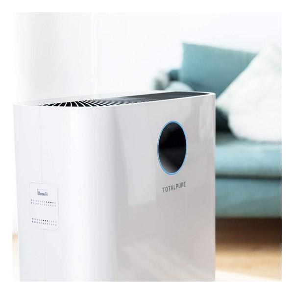 Purificatore d'aria bianco con un cerchio blu e il testo Totalpure. Lo sfondo è una stanza.
