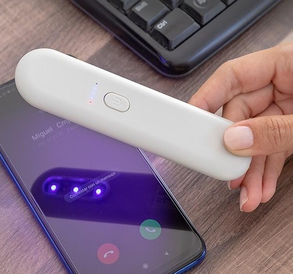Ein weißes UV-Licht-Desinfektionsmittel desinfiziert einen Telefonbildschirm.