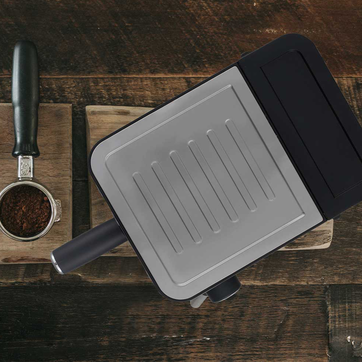 Ekspres do kawy z kolbą i fusami na drewnianej powierzchni.