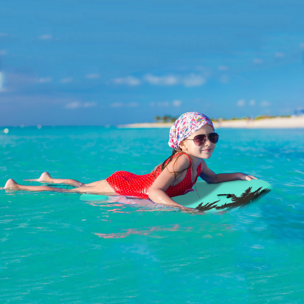 Ein Mädchen auf einem Surfbrett in türkisfarbenem Wasser. Sie trägt eine Sonnenbrille und einen roten Badeanzug.