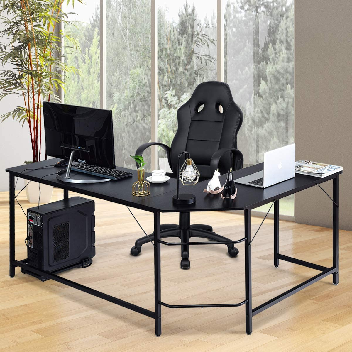 Ein L-förmiger schwarzer Schreibtisch mit Computer, Monitor und Laptop, mit schwarzem Stuhl und Fensterblick.
