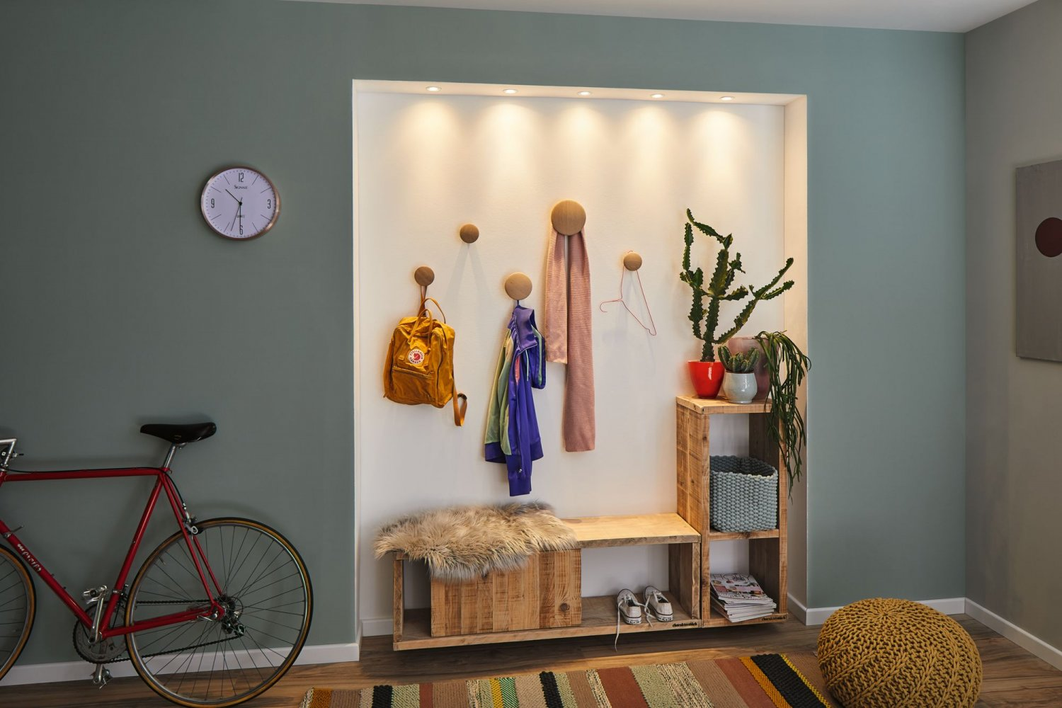 Stilvolles Interieur mit rotem Fahrrad, Bank mit Fell und Wandhaken mit Gegenständen, neben einer Uhr.