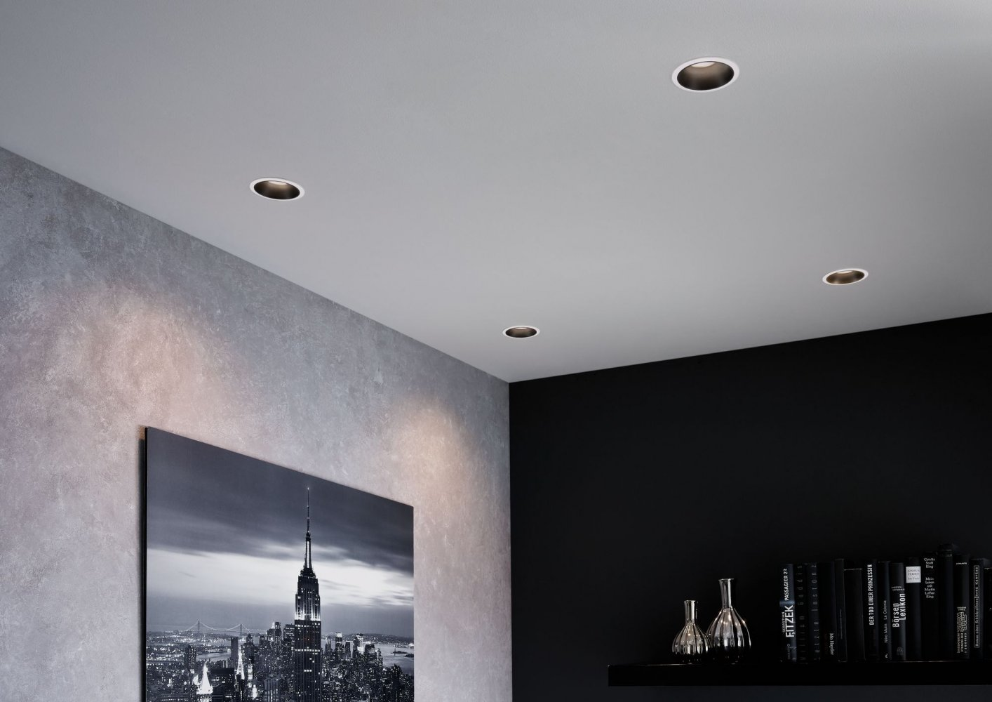 Modernes Zimmer mit mehreren Einbauleuchten in der Decke. Wandkunst links.