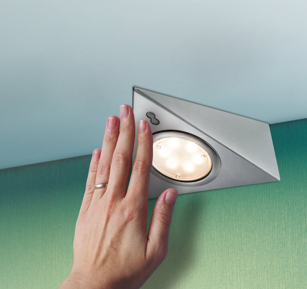 Eine Hand greift nach einer eingelassenen, silbernen, dreieckigen Deckenleuchte. Grüne Wand und hellblauer Decke.