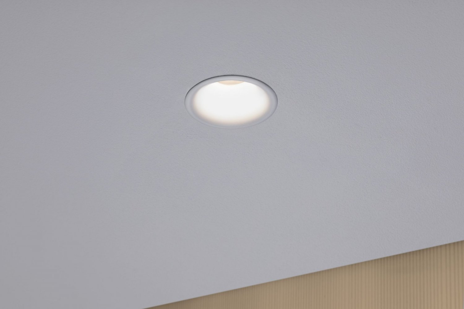 Ein Einbaustrahler, der nach unten auf eine weiße Decke leuchtet.