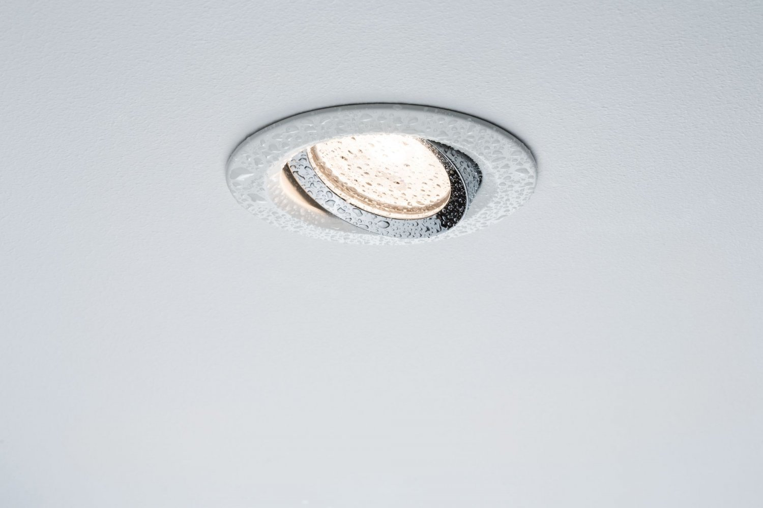 Ein Einbaustrahler, Chrom-Finish, mit Wassertröpfchen-Detail.