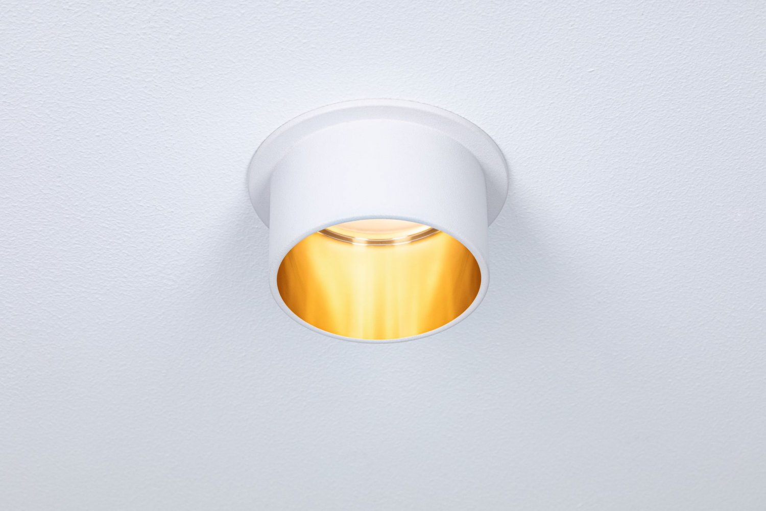 Eine weiße Einbauleuchte, die in einer weißen Decke installiert ist, wobei das Licht von innen emittiert wird.