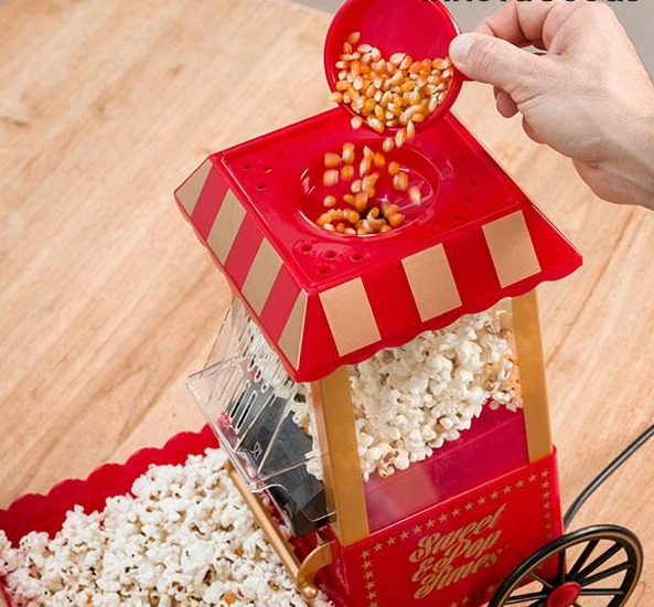Popcornmaschine, in die Popcorn gegossen wird. Rotes und goldenes Farbschema.