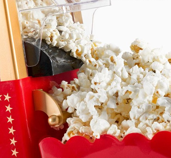 Popcorn, das aus einer roten Popcornmaschine quillt. Sterne sind auf der Maschine.
