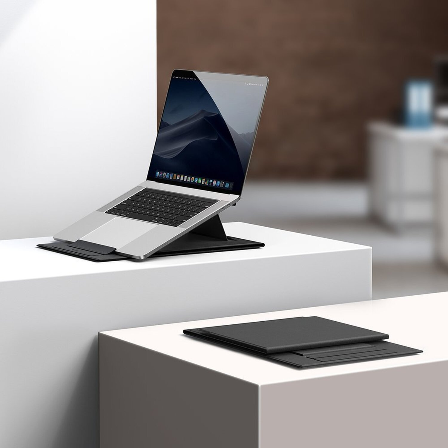 Laptop auf einem schwarzen Ständer auf weißer Plattform. Ein zweiter, zusammengeklappter Ständer. Weißer Hintergrund.