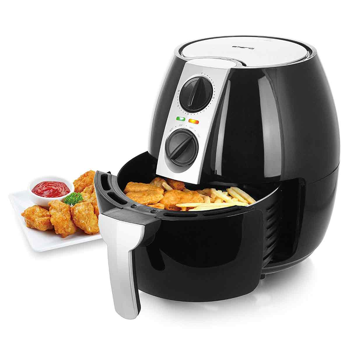 Schwarze Heißluftfritteuse mit Essen darin und einem Teller mit frittiertem Essen und Ketchup daneben.