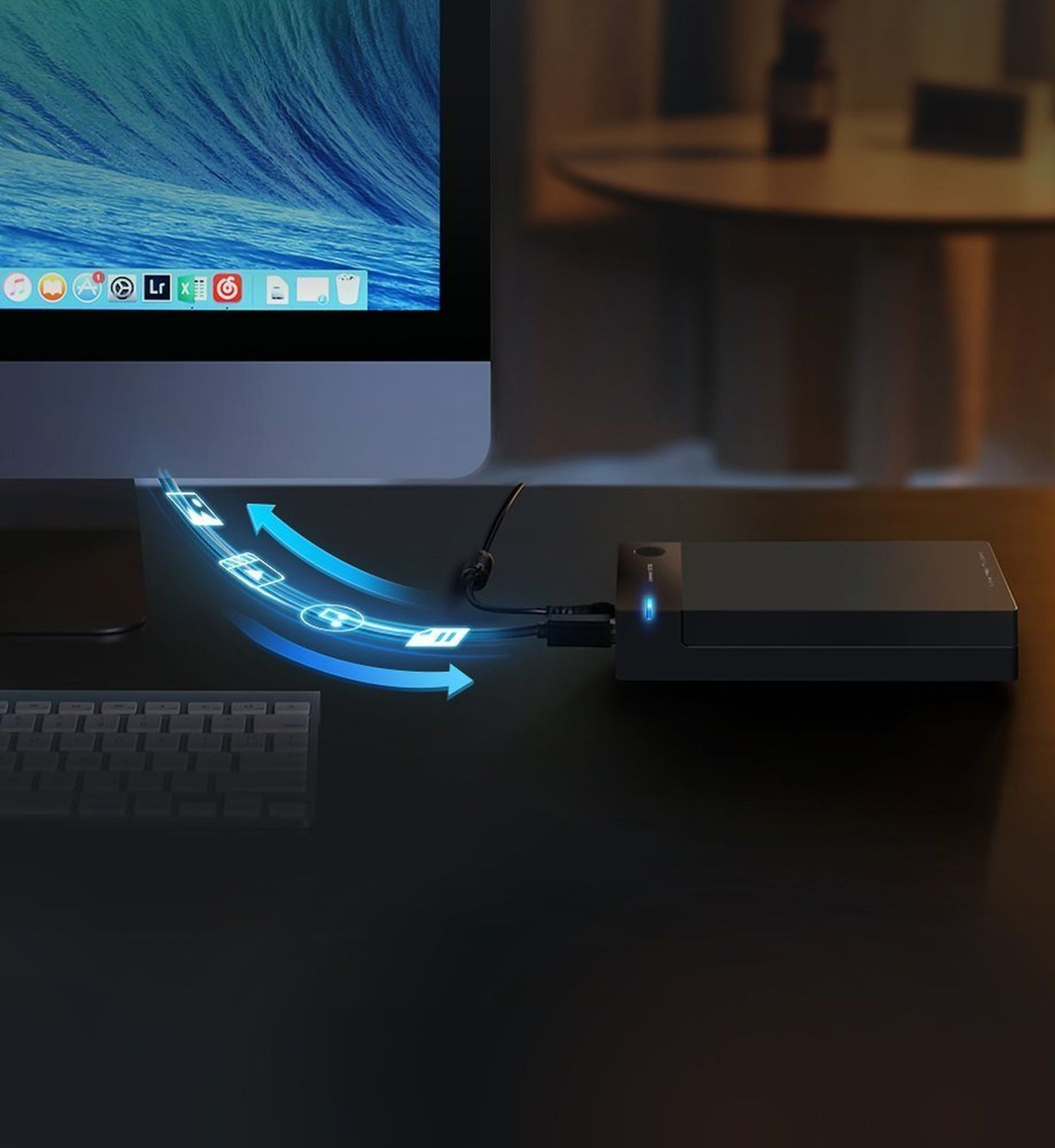 Ciemny układ biurka z komputerem, zewnętrznym dyskiem twardym połączonym niebieskimi strzałkami.