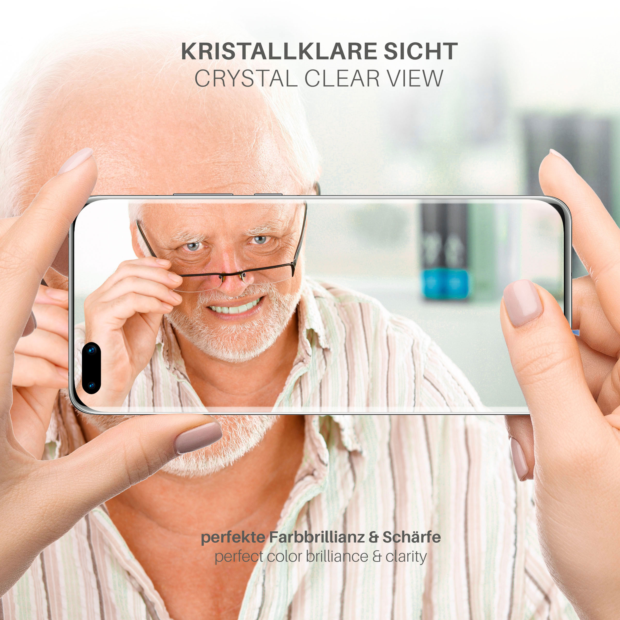 Ein Mann mit Brille hält ein Telefon mit Displayschutzfolie, lächelnd, vor neutralem Hintergrund.